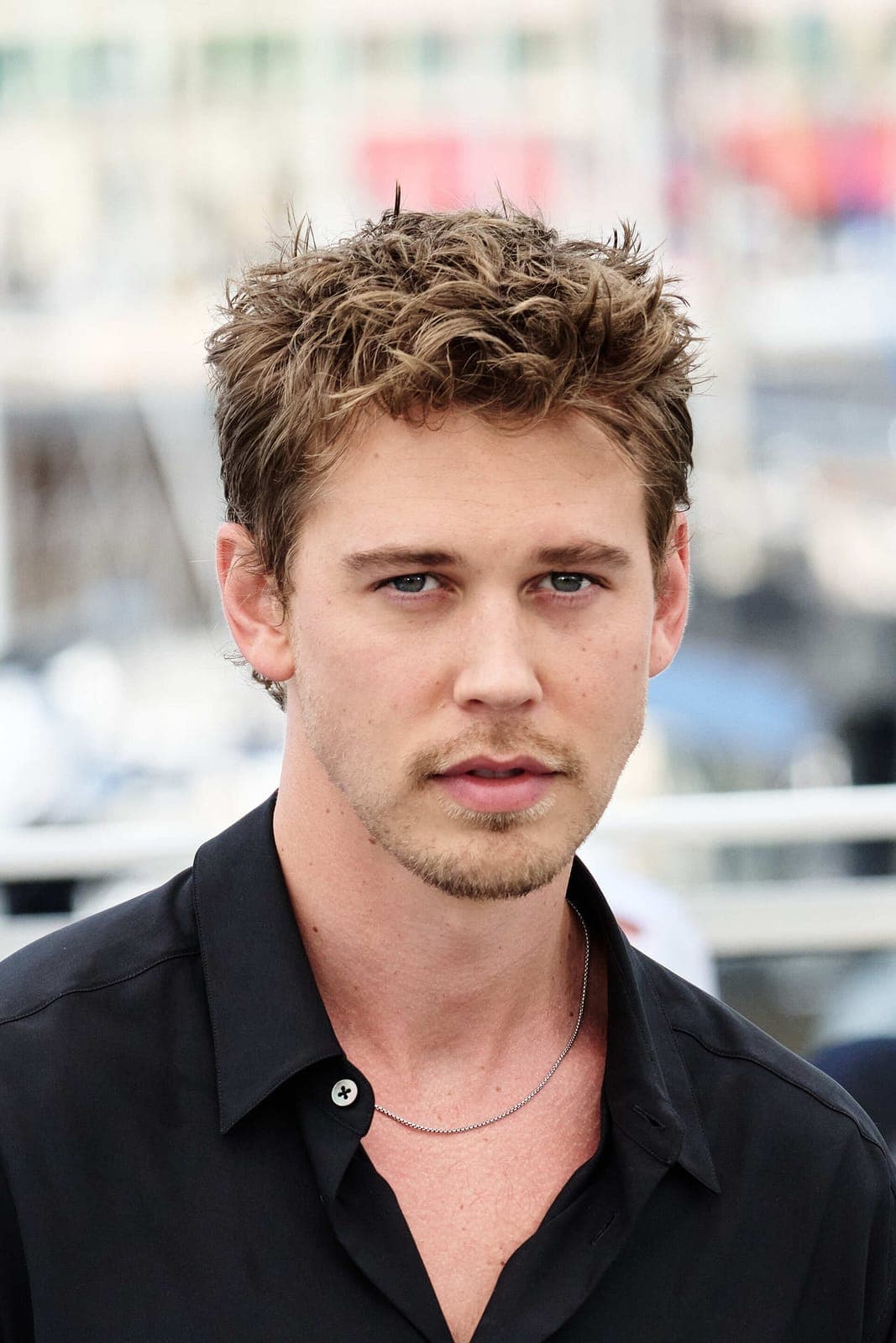 Cannes cropped frontal — sharp jaw taper, high cheekbones, soft smile under festival flash.