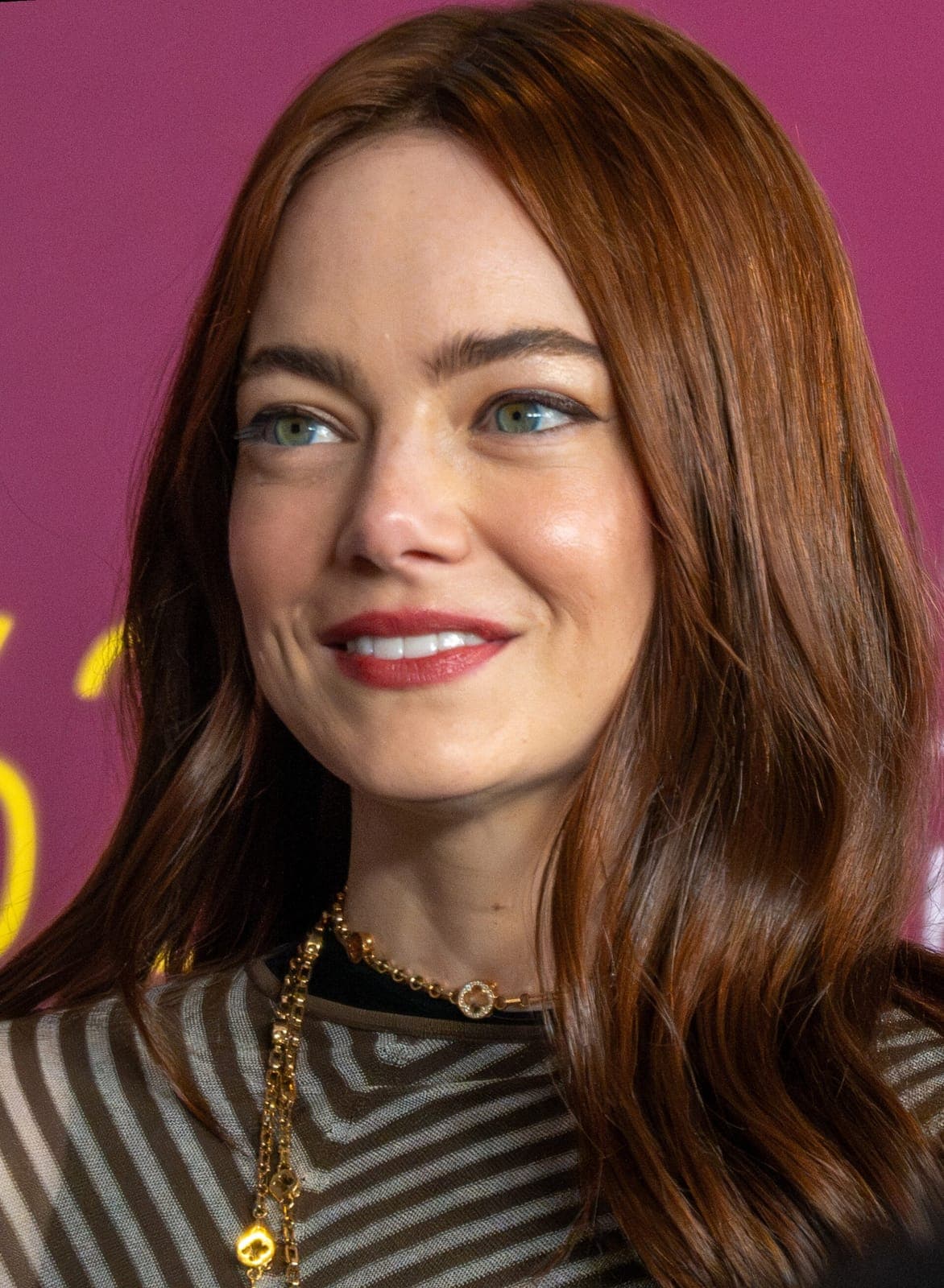 Auburn wave frame — freckles, green eyes, and soft-smile under high-key press light.
